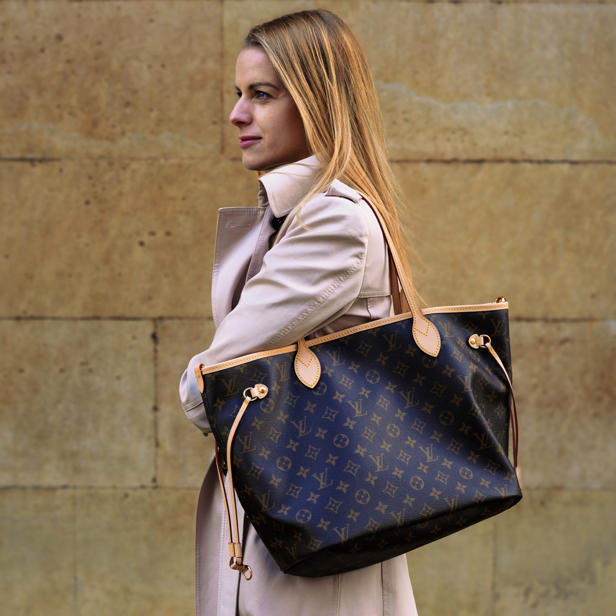 A woman carrying a brown Louis Vuitton bag on her shoulders