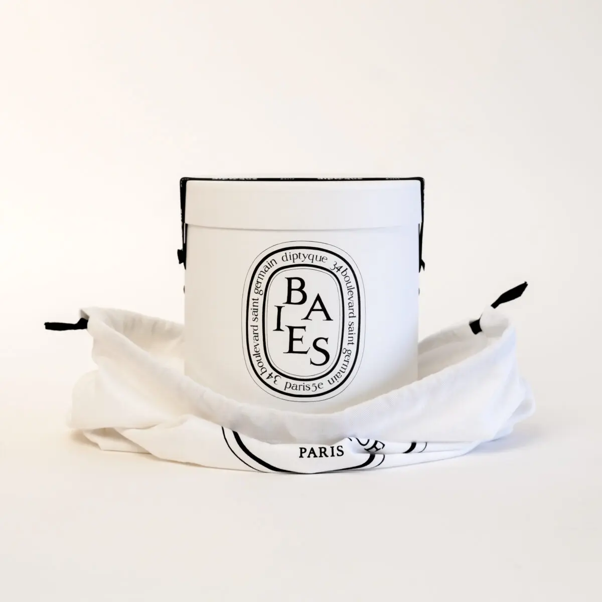 A white Diptyque candle in a round container with a fabric covering