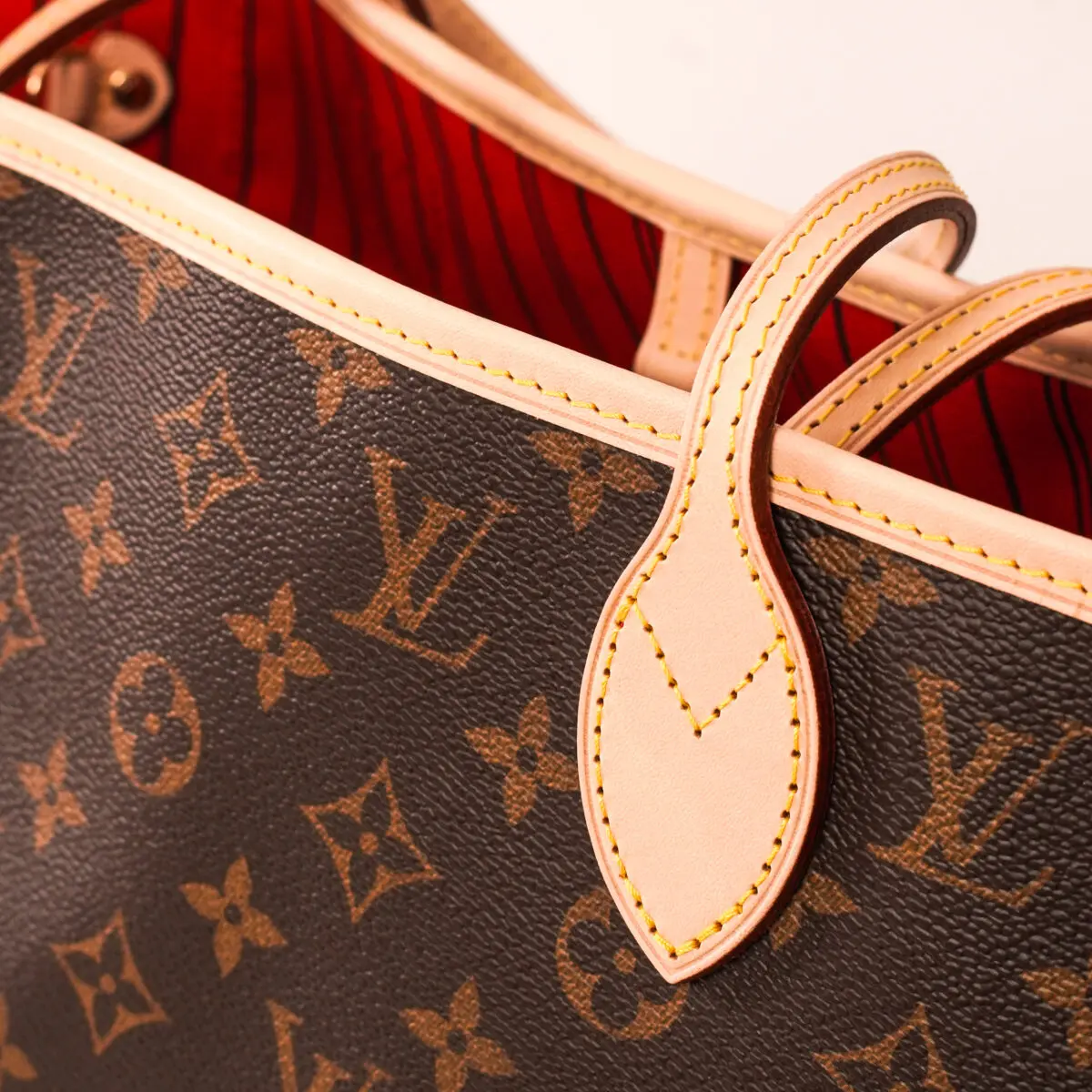A close-up shot focuses on the details of a Louis Vuitton Neverfull handbag