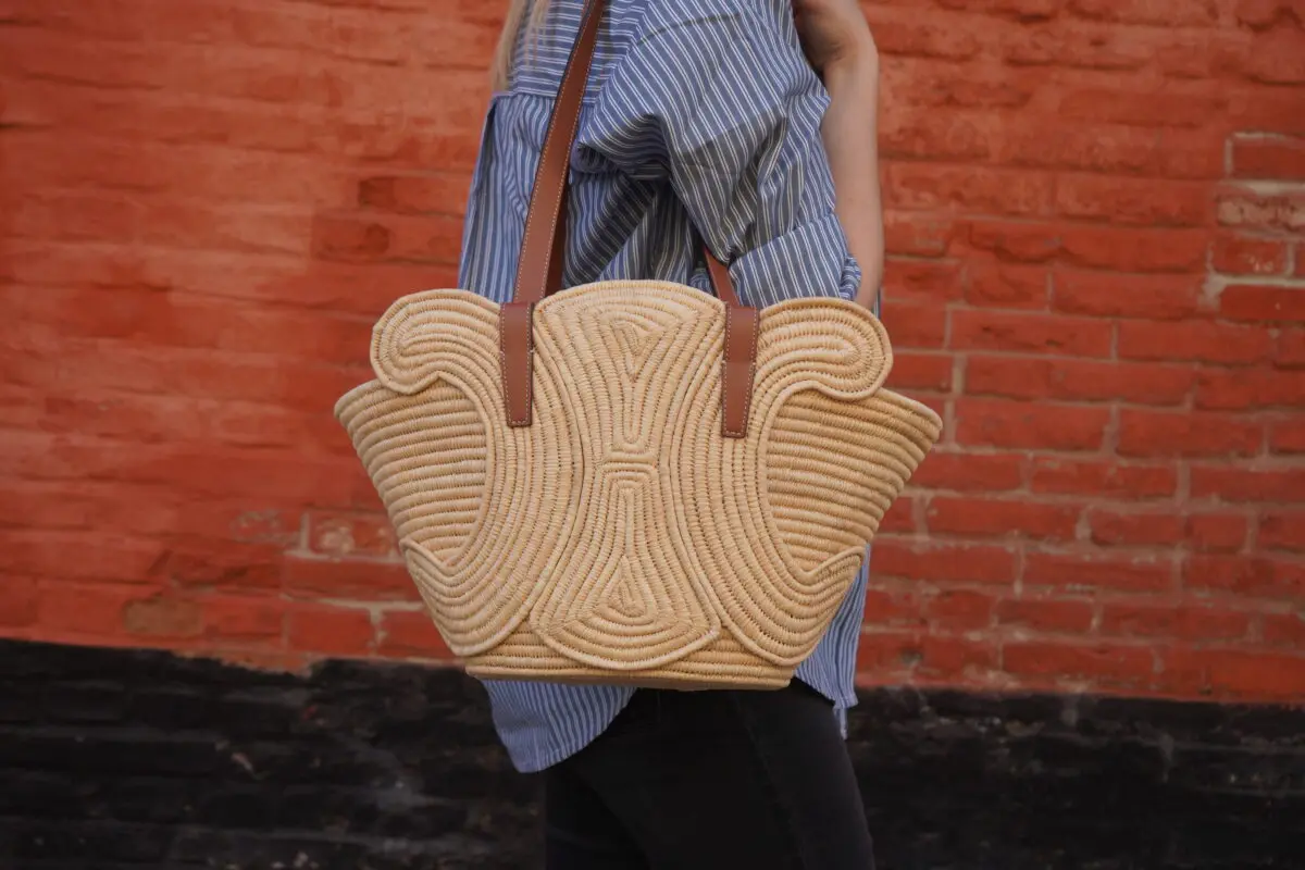 a large, light tan woven straw Celine tote bag with brown leather shoulder straps. The bag features a distinctive, stylized geometric pattern woven into its front