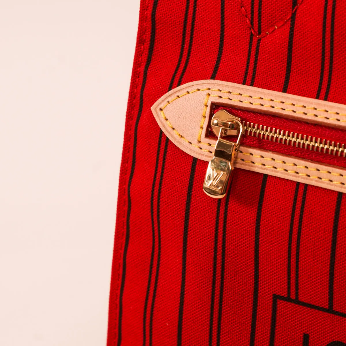A detailed close-up focuses on the zipper of a Louis Vuitton Neverfull MM bag
