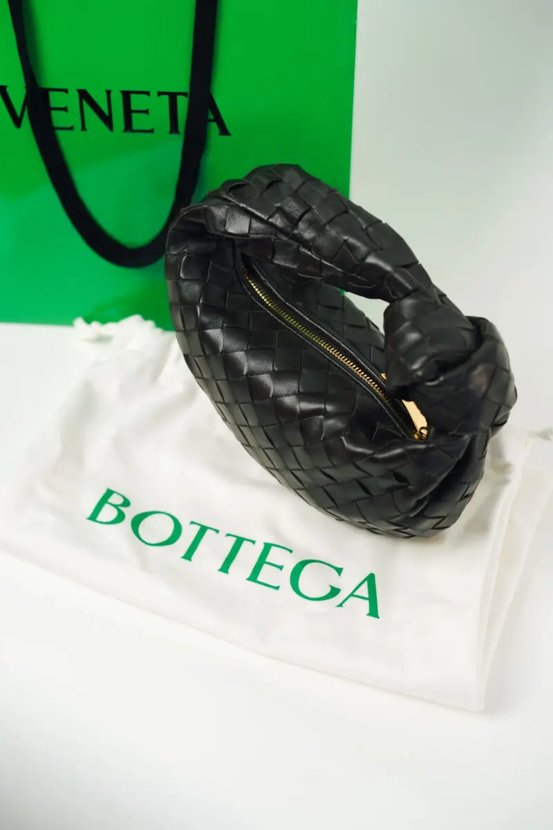 Image of a Bottega Veneta Mini Jodie Bag in front of Bottega packaging in green.