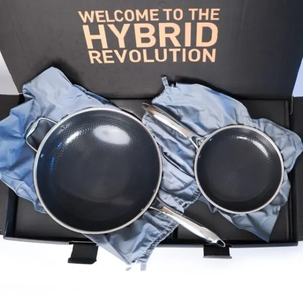 Two grey frying pans with silver handles are in a black box. The box lid says "WELCOME TO THE HYBRID REVOLUTION
